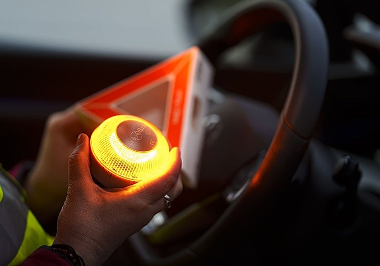 Una conductora con una baliza V-16 en el interior de un vehículo.