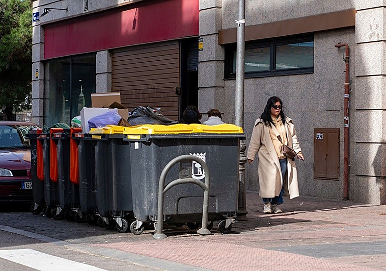 Una vecina pasea junto a unos cubos de basura de Puente de Vallecas