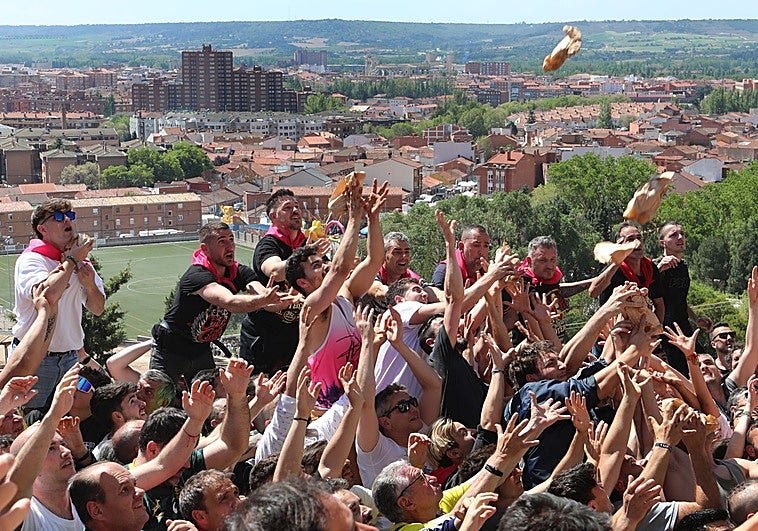 Decenas de personas intentan coger una de las miles de bolsas de pan y quesillo lanzadas a los pies del Cristo del Otero en Palencia