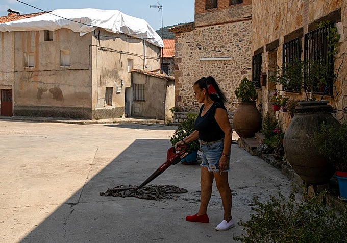 Una vecina limpia las cenizas que ha dejado el incendio en le pueblo.
