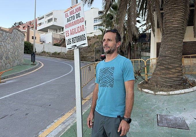 Pablo junto a uno de los carteles que han colocado los vecinos. Detrás, las vallas amarillas que funcionan como segunda medida de protección en la entrada