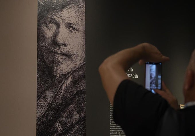 Un hombre fotografiando una de las obras de la exposición 'Rembrandt. Un mundo en grabados', en CaixaForum València