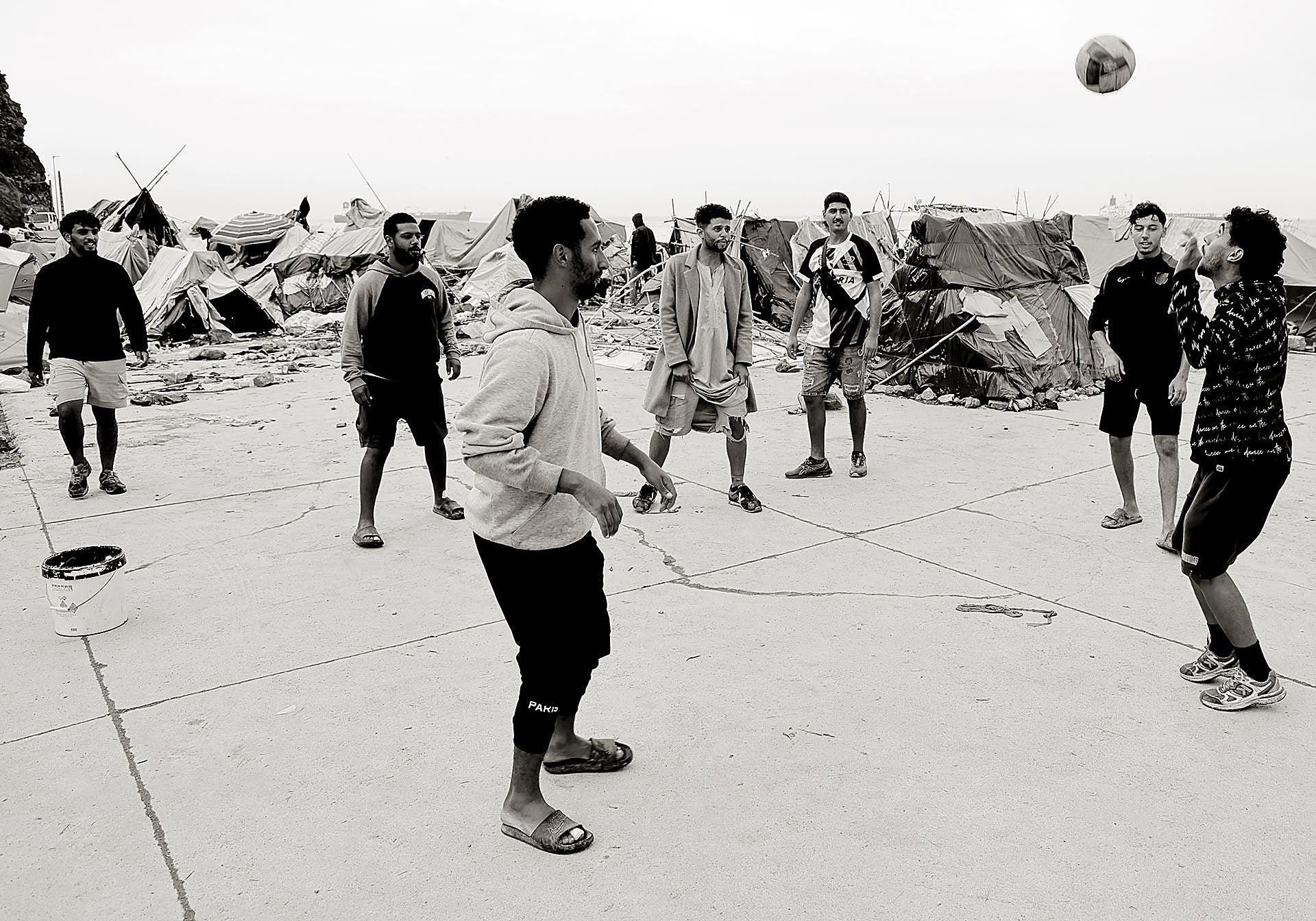 Varios inmigrantes juegan con un balón entre tiendas de campaña