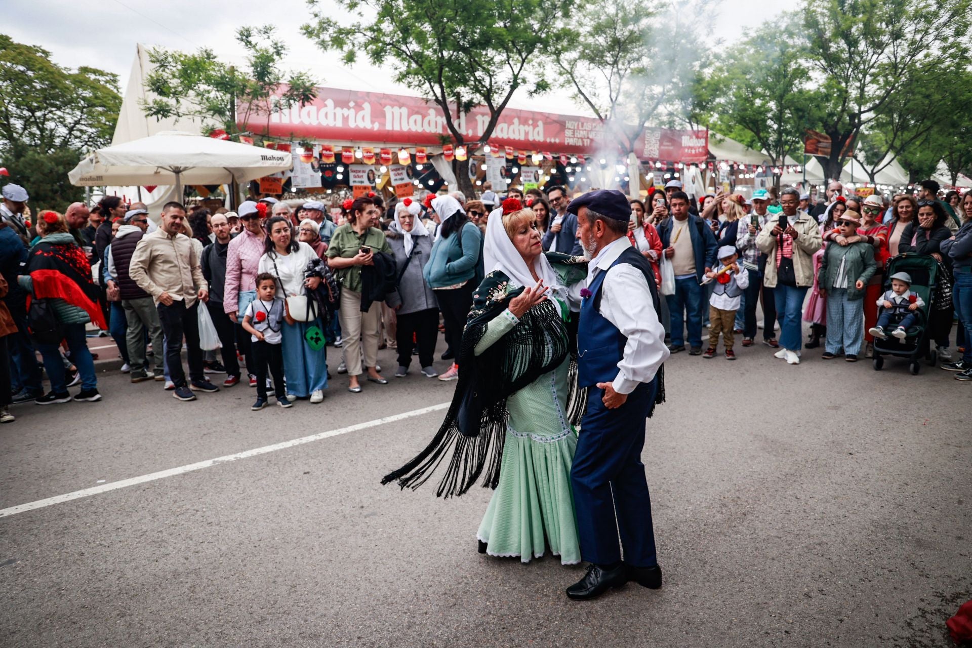 Dos chulapos bailan un chotis rodeados de personas en la Pradera de San Isidro