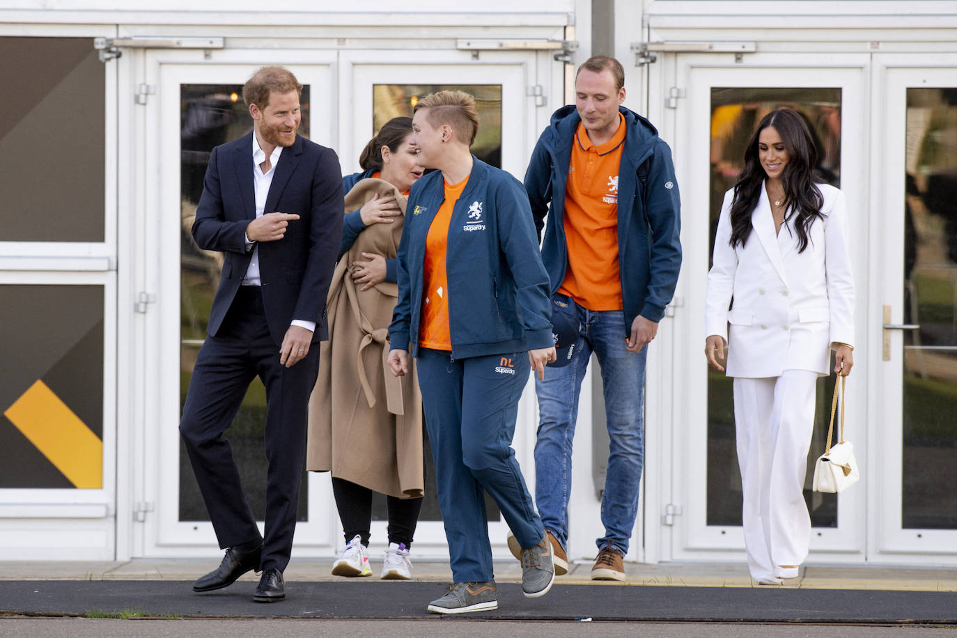 En su llegada a Países Bajos para el evento en homenaje a los soldados heridos , la duquesa de Sussex deslumbraba con un espectacular traje blanco de Valentino de estilo minimalista. Lo acompañaba con un bolso del mismo diseñador en tono también blanco y detalles geométricos en dorado. 
