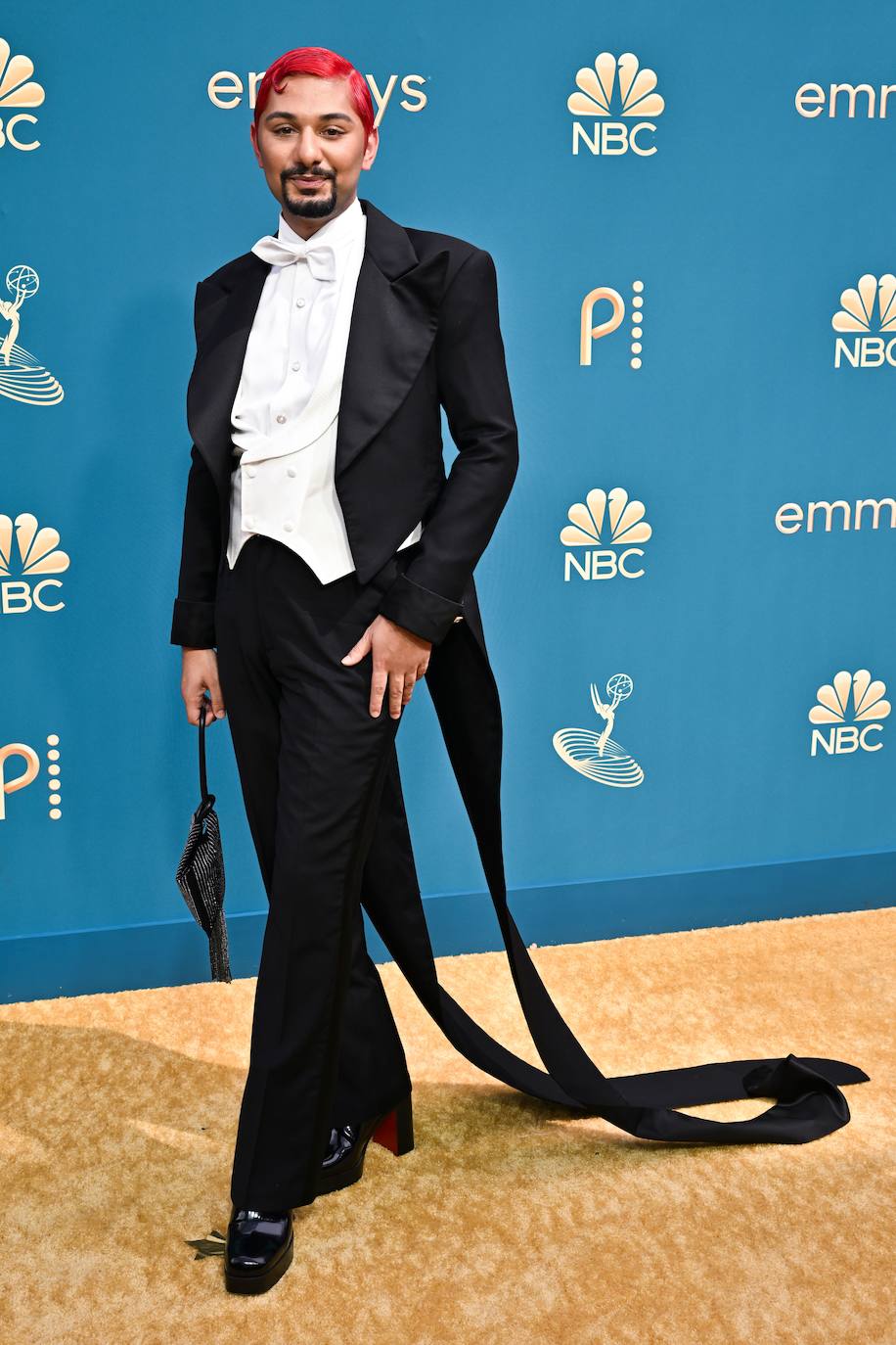 Mark Indelicato  ha posado con un traje de corte inusual, tacón y bolso negros. El actor ha dado el toque de color con un peinado rojo intenso