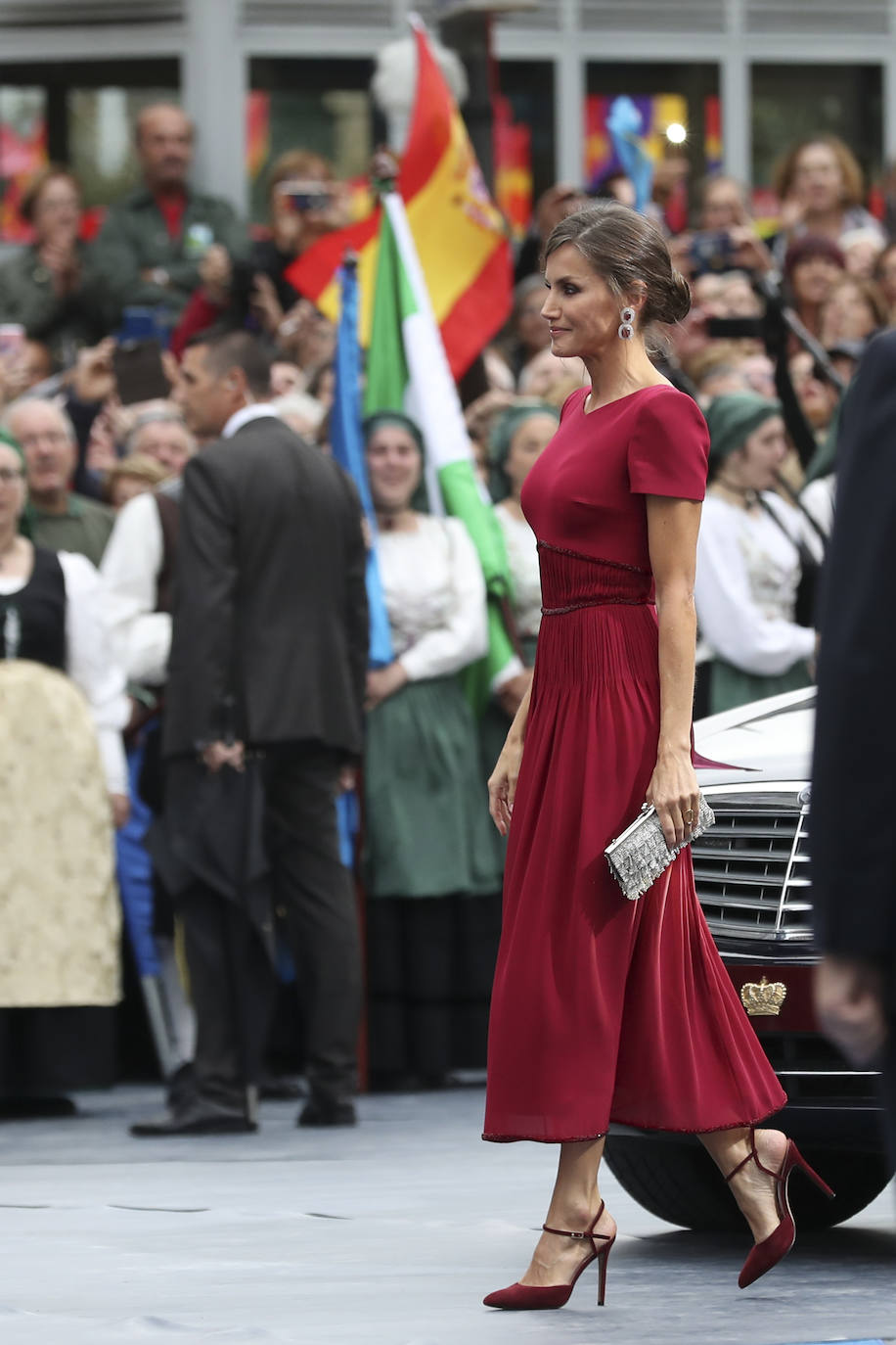 Uno de los colores favoritos de la Reina y no dejó escapar la ocasión de lucirlo para los Premios Princesa de Asturias 2019, un evento muy especial ya que la princesa Leonor debutaba con su primer discurso en este acto. El vestido de manga corta con plisado y pedrería a la altura de la cintura lo firmaba Felipe Varela, y los zapatos del mismo color eran de Lodi. Lo combinó con un bolso de mano en color plateado.