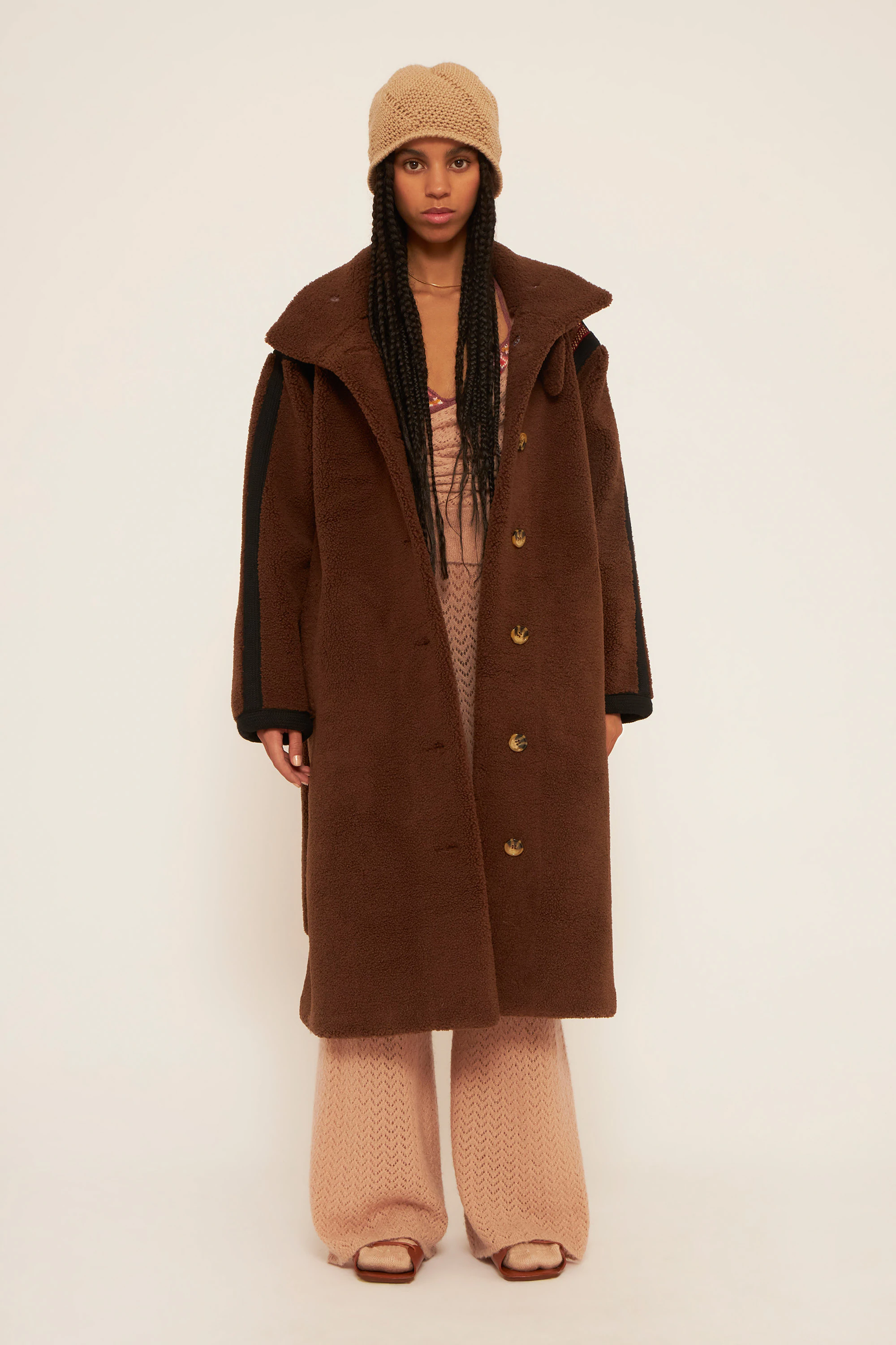 Abrigo largo de piel sintética marrón, con dos bolsillos delanteros y cierre con botones de Antik Batik. Disponible por 420 euros.
