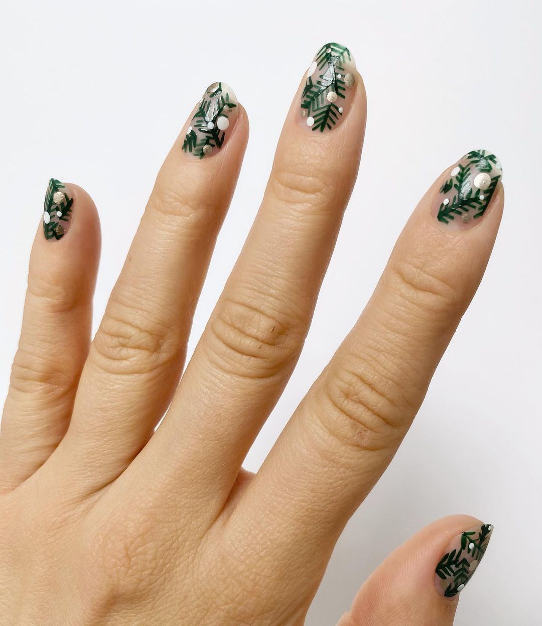 Manicura típicamente navideña que reproduce las ramas de abeto en color verde, con unos puntitos blanco asemejando los copos de nieve. 