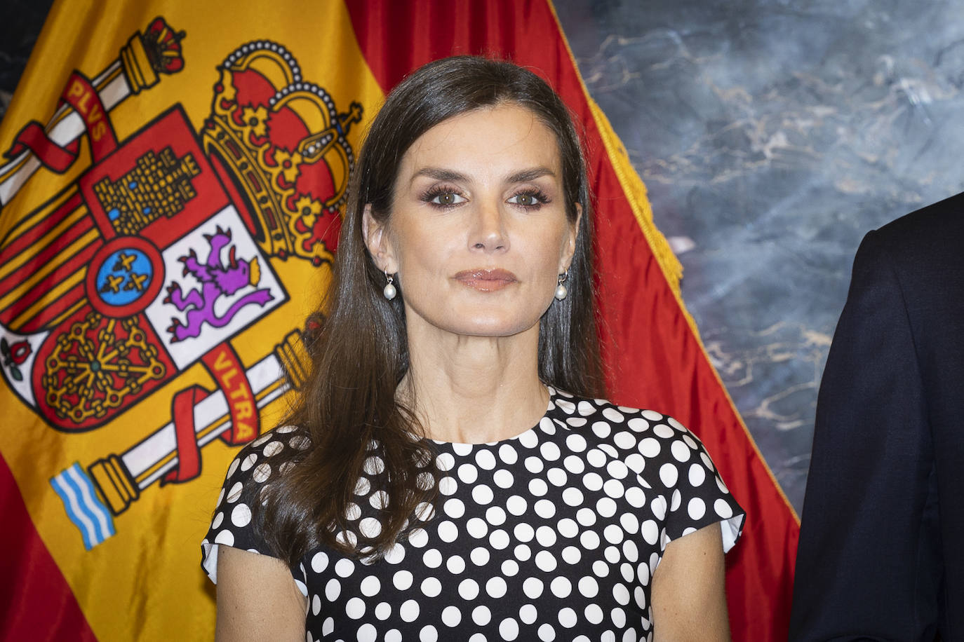 Doña Letizia combinó el vestido de lunares con pendientes de aro y una perla colgante de Pandora (están a la venta en su web por 99 euros). Dejó su melena suelta y lució un favorecedor maquillaje, con una piel luminosa y perfecta, un pintalabios nude con acabado brillo y su habitual mirada marcada con lápiz de ojos y máscara de pestañas.