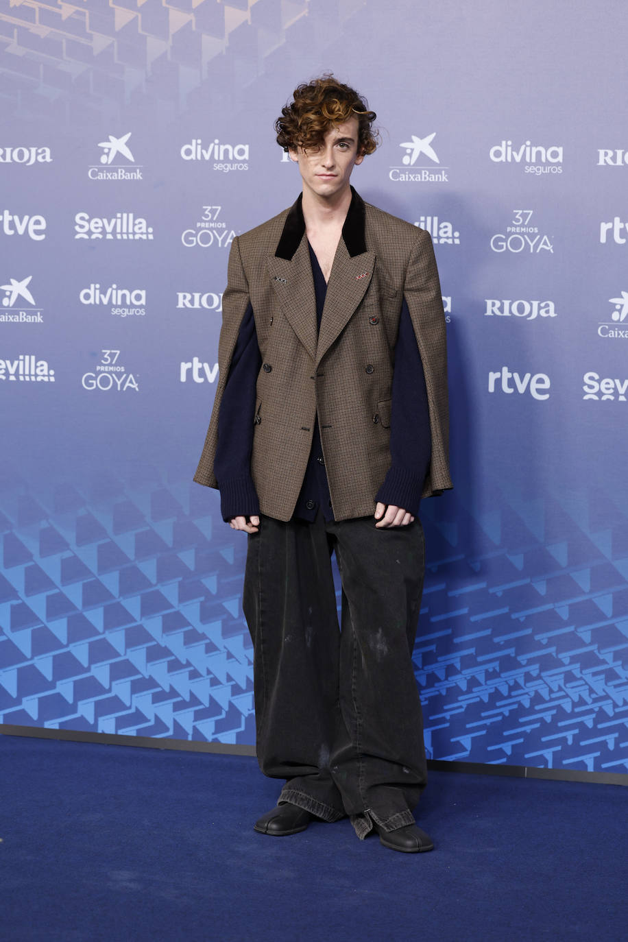 El cantautor Alvaro Lafuente Calvo, conocido como Guitarricadelafuente, ha elegido un estilismo bastante complicado: blazer marrón con doble manga y pantalones vaqueros anchos. Es de Maison Margiela. 