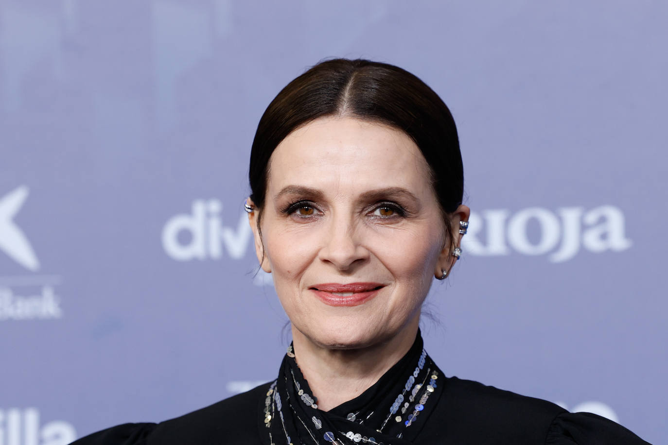 Juliette Binoche, Goya de Honor, posó en la alfombra roja con recogido con raya en el medio y un favorecedor maquillaje con ojos ahumados en tonos grises metalizados y labios naturales. 