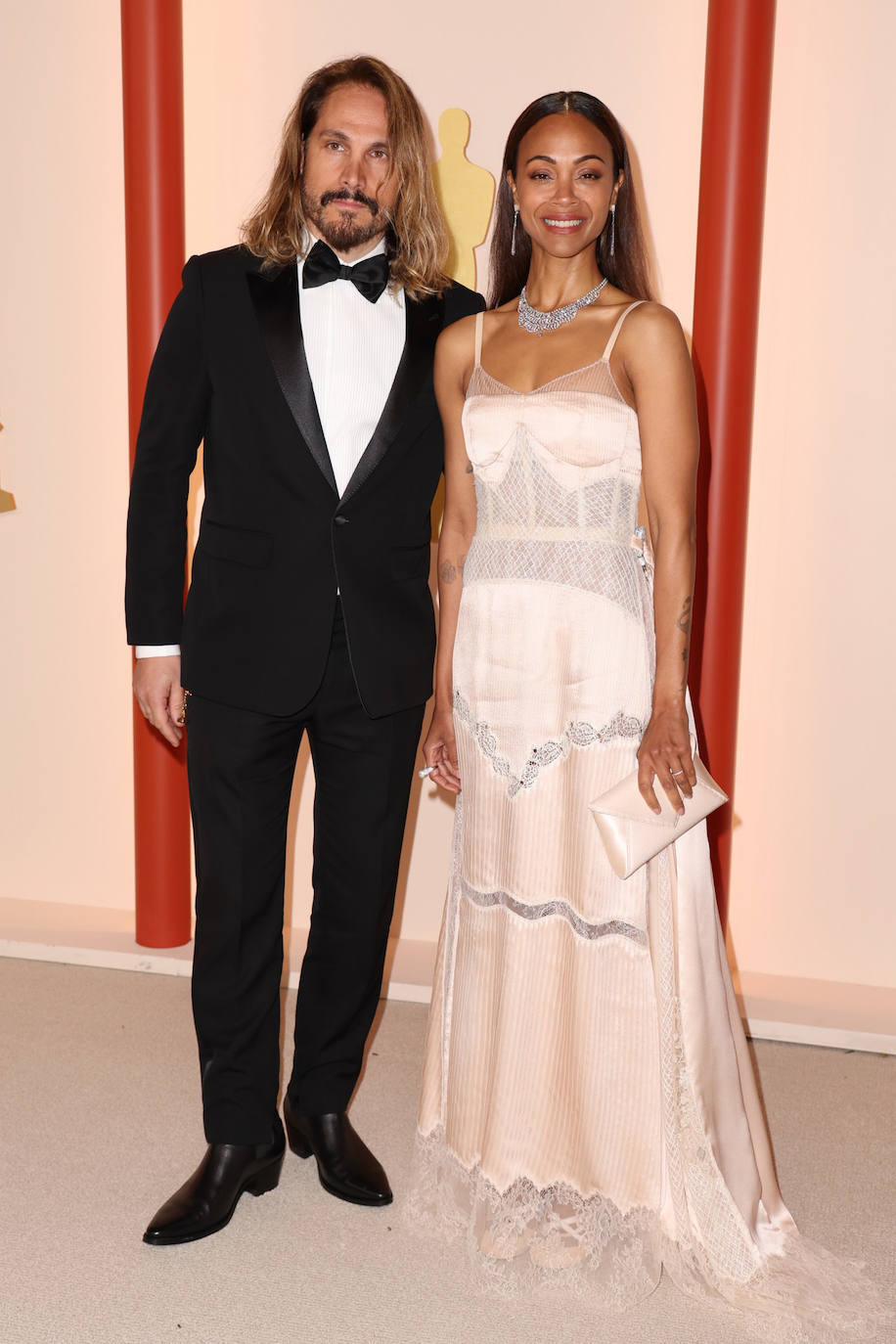 Zoe Saldana -con un vestido lencero de Fendi- con su marido, Marco Perego. El modelo elegido está elaborado en de satén de seda rosa pálido y lleva un corsé.