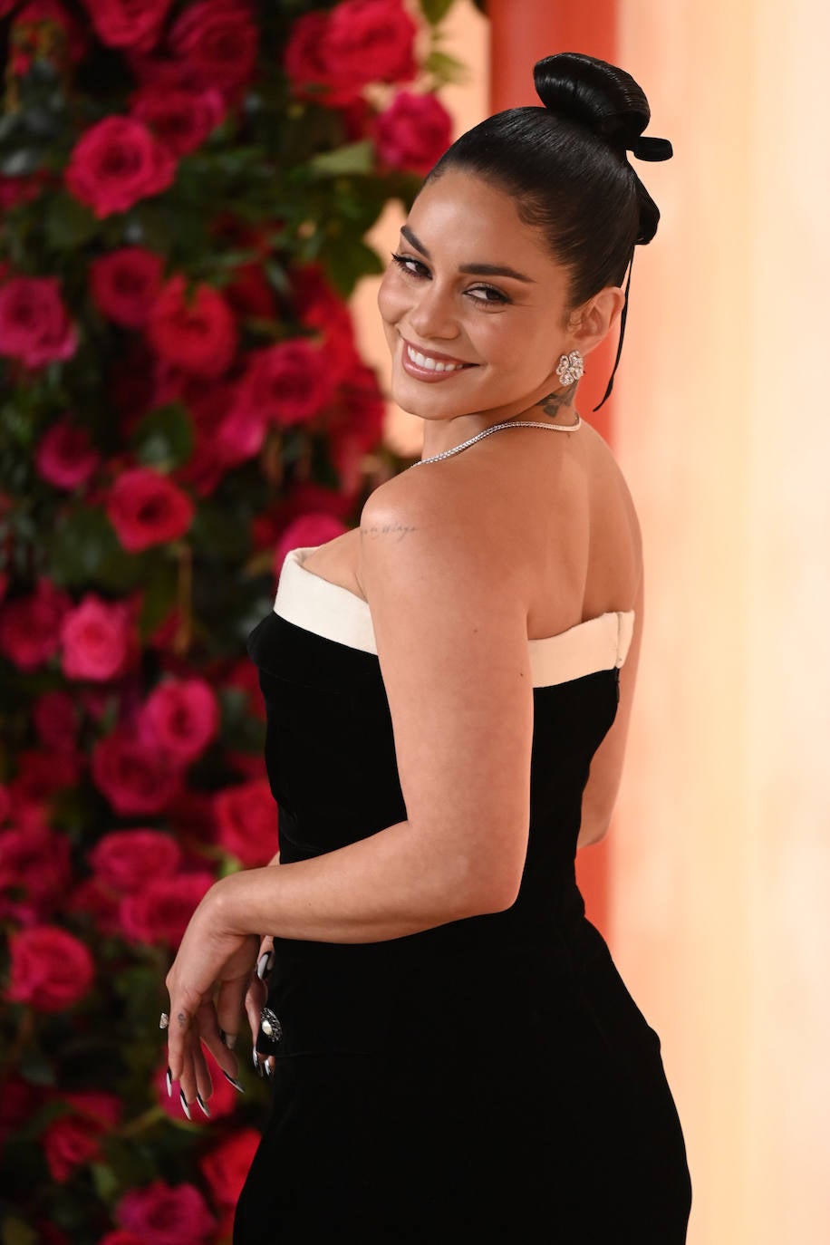 Vanessa Hudgens lució un moño alto o 'top knot' adornado con un lazo negro, con todo el pelo muy pulido y brillante. En cuanto al maquillaje se decantó por un look natural con varias capas de máscara de pestañas y labios nude.  