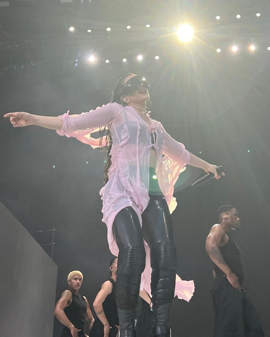 Rosalía durante su actuación en el Festival de Coachella 2023. La artista española lució pantalones de cuero y top negro, con camisa rosa transparente. 