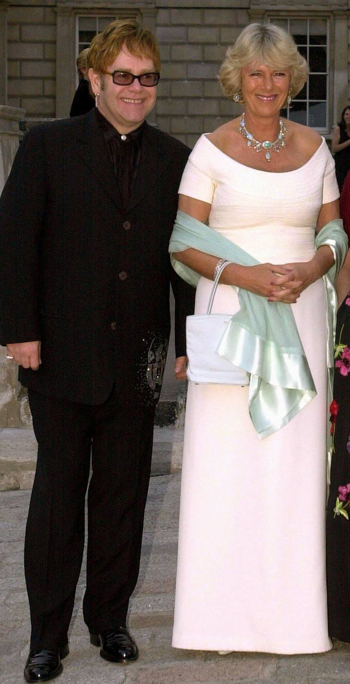 Camilla, con vestido de fiesta en color rosa y complementos en verde agua, junto a Elton John. 