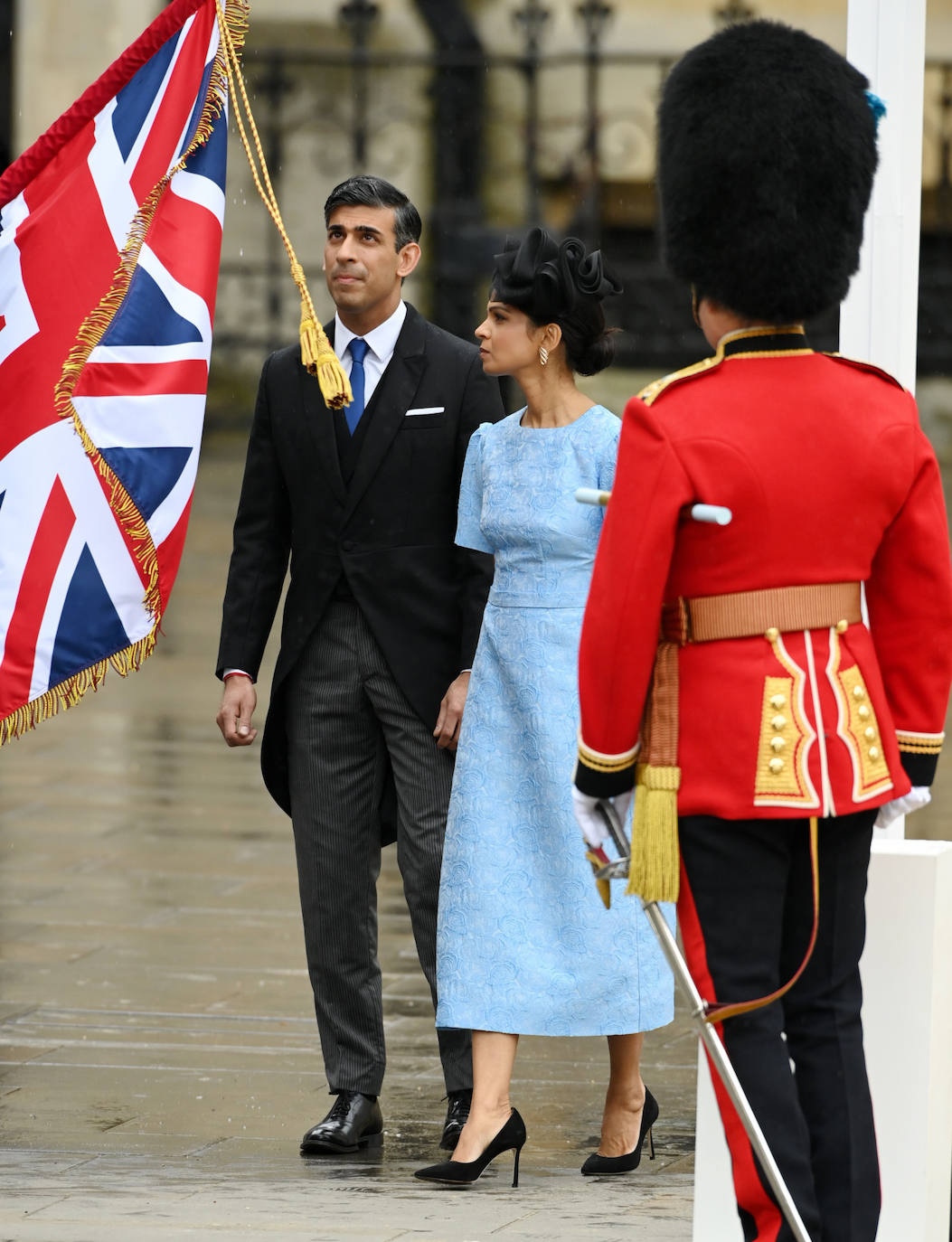 El primer ministro británico y su esposa que ha elegido un bonito vestido en color azul celeste y tocado en color negro. 