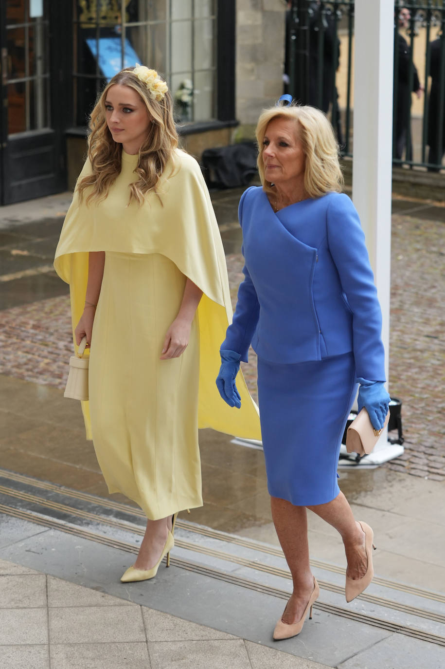 Jill Biden ha lucido un dos piezas en color azul con guantes del mismo tono, y zapatos y bolso en rosa pastel. Su nieta ha elegido un vestido con capa en color amarillo y tocado del mismo tono. 