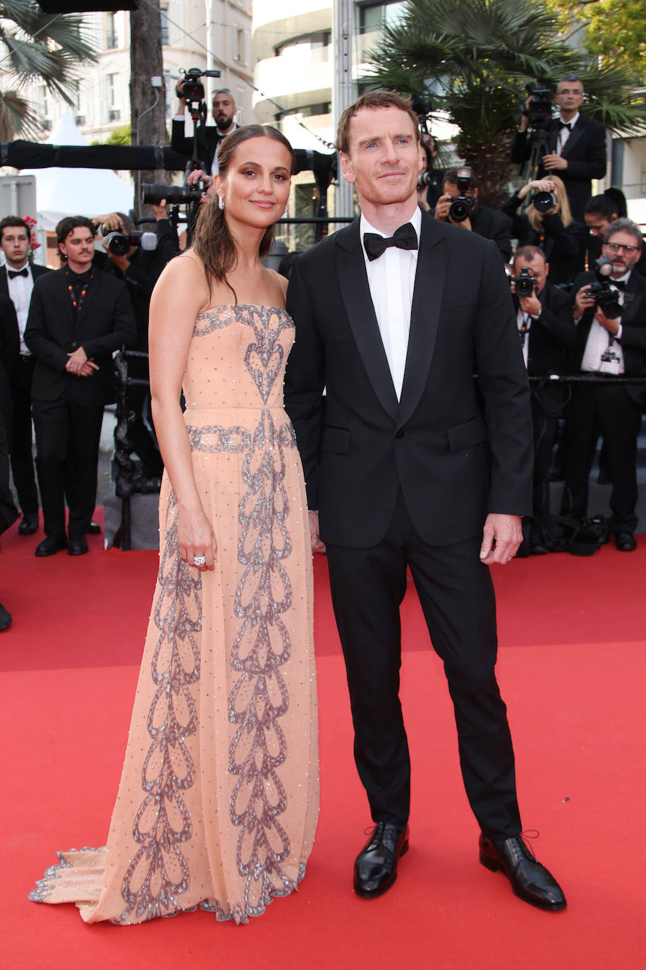 Alicia Vikander posó con un vestido de seda bordado con cristales de Louis Vuitton que combinó con joyas de la misma firma. Michael Fassbender llevó un esmoquin negro con camisa blanca.