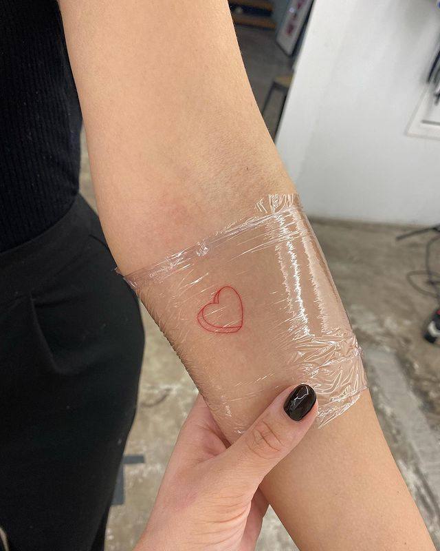 Tatuaje de línea fina en color rojo. La tatuadora es Andrea Delgado. 