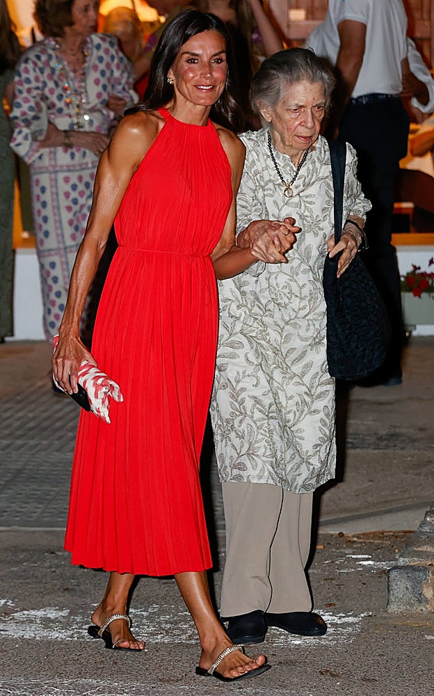 La Reina Letizia con un bonito vestido rojo plisado, sandalias planas y bolso de mano de firma mallorquina. Del brazo, la Princesa Irene.