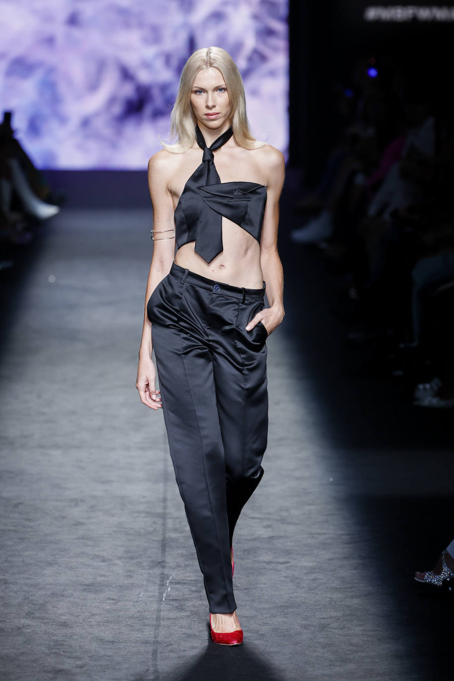 Desfile de Paloma Suárez en la MBFWMadrid primavera-verano 2024. Elegante conjunto con pantalón y top en forma de corbata en negro satinado. 