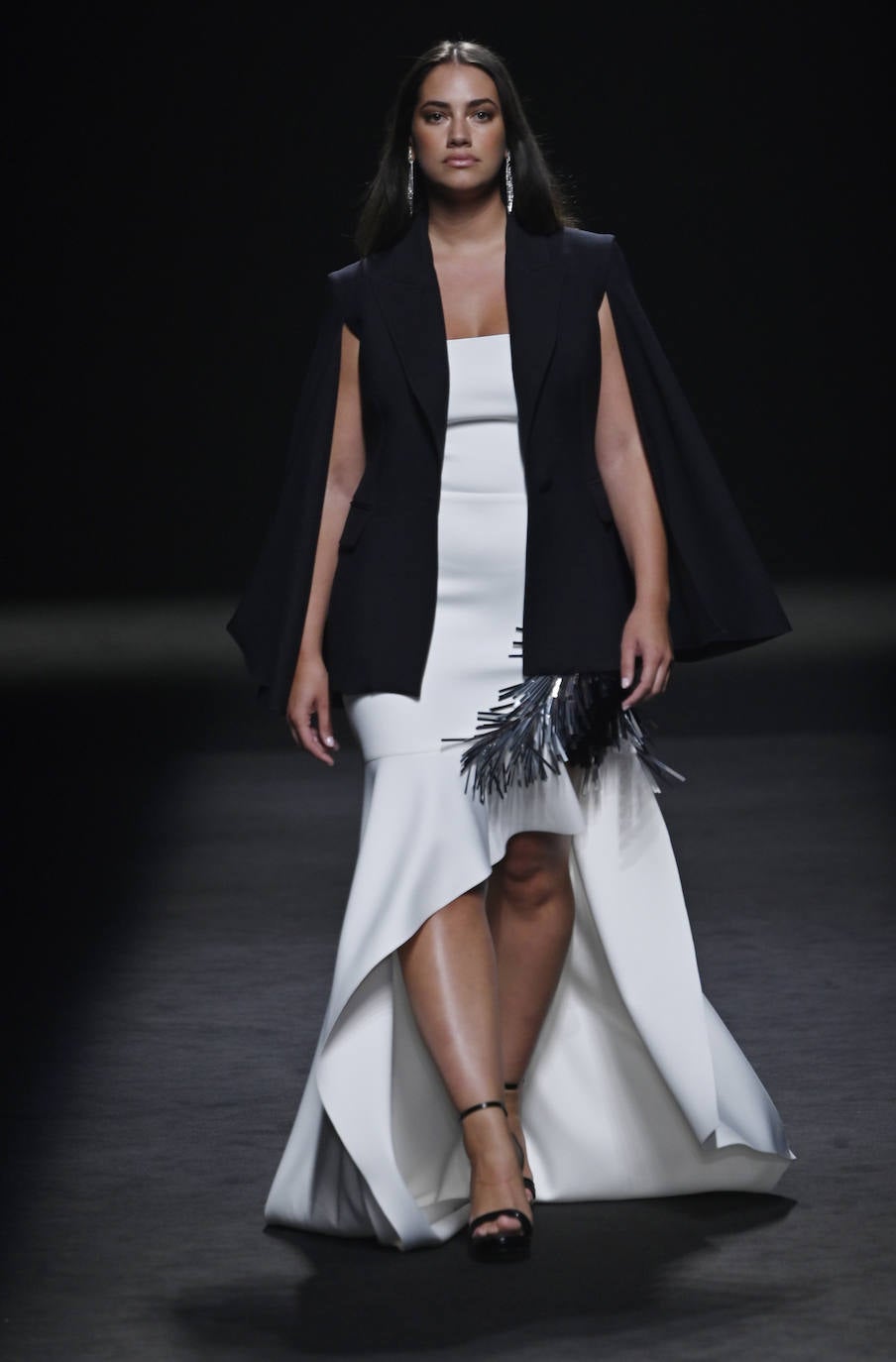 Desfile de Isabel Sanchís en la MBFW Madrid Primavera/Verano 2024. Uno de los diseños de la nueva colección, que combina un vestido asimétrico con un chaleco negro y plumas. 