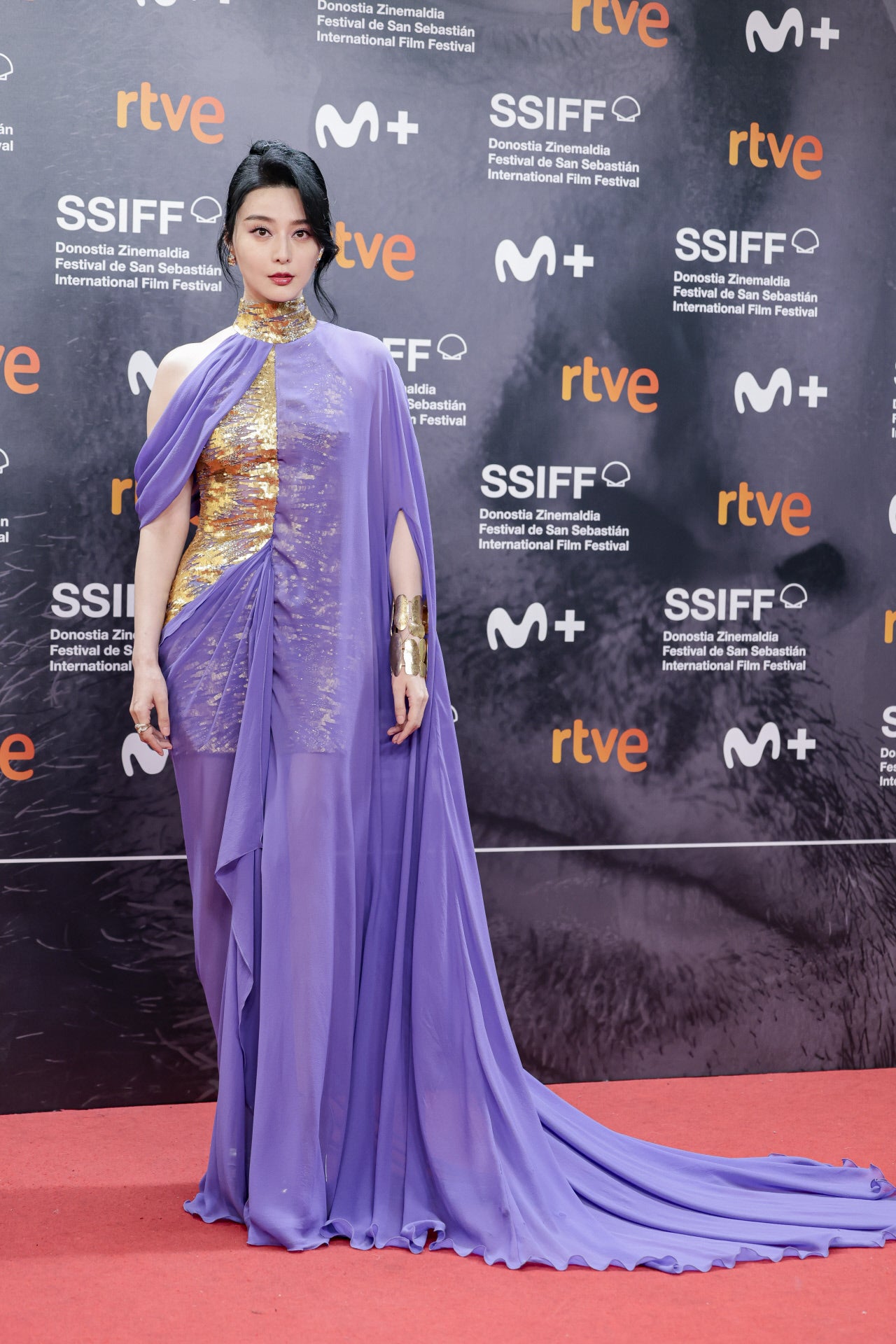 Una de las asistentes a la gala de clausura se decantó por un llamativo estilismo con cuerpo dorado combinado con una capa de seda en color lila. 