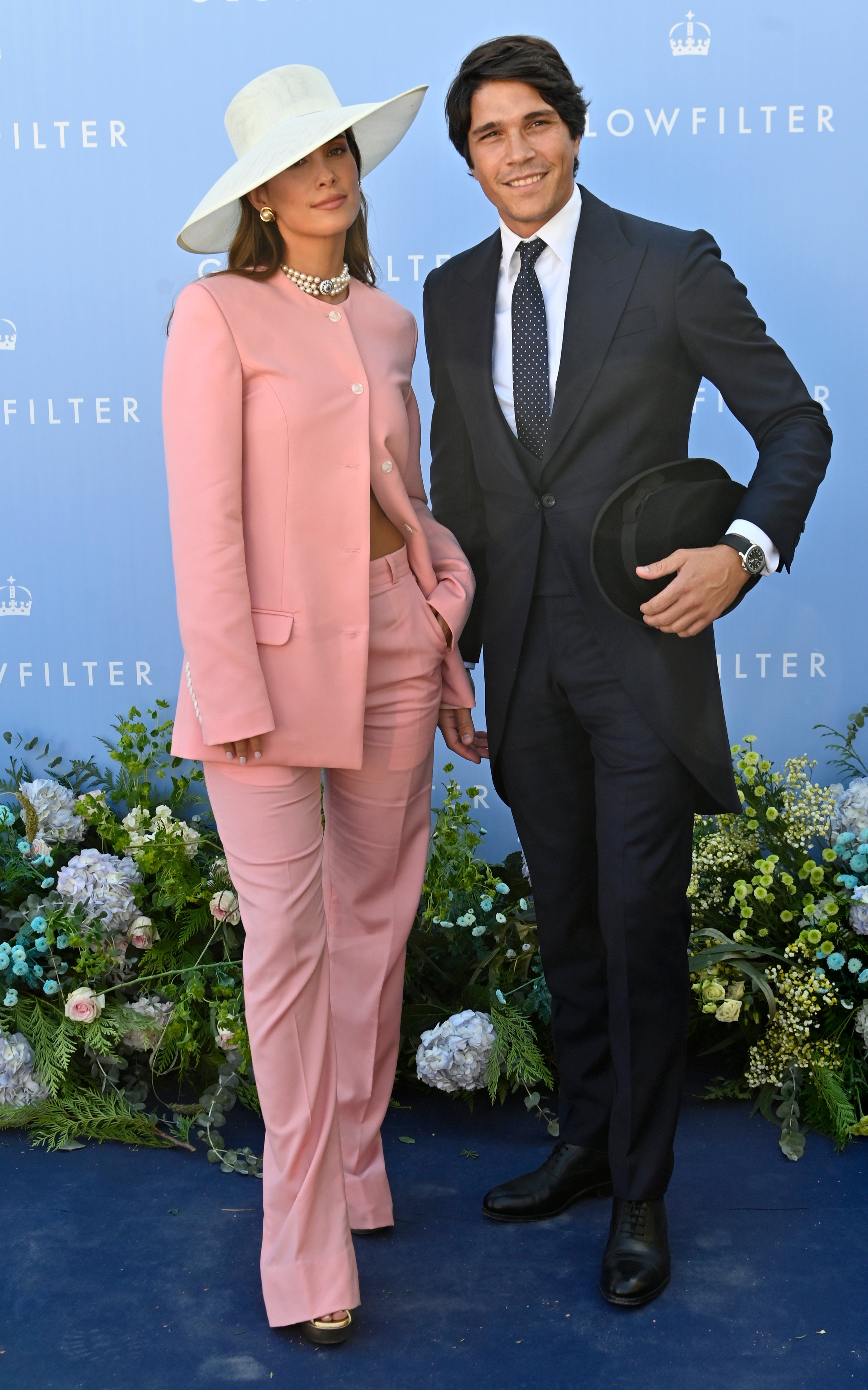 María Pombo junto a su marido Pablo Castellanos. La influencer llevó un dos piezas de chaqueta cerrada a la mitad y pantalón largo firmado por Mans, pamela de Lolita MacTisell y collar de Joyas Antiguas Sardinero.