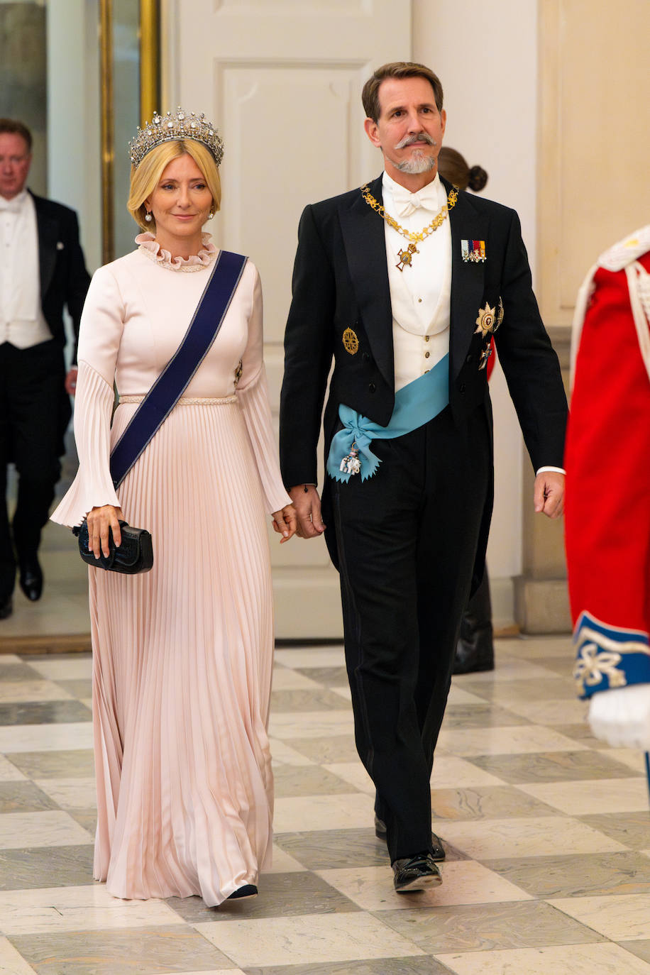 Marie Chantal se decantó por un vestido de color rosa con manga larga y falda plisada, que combinó con clucht y zapatos negros y una espectacular tiara de diamantes. 