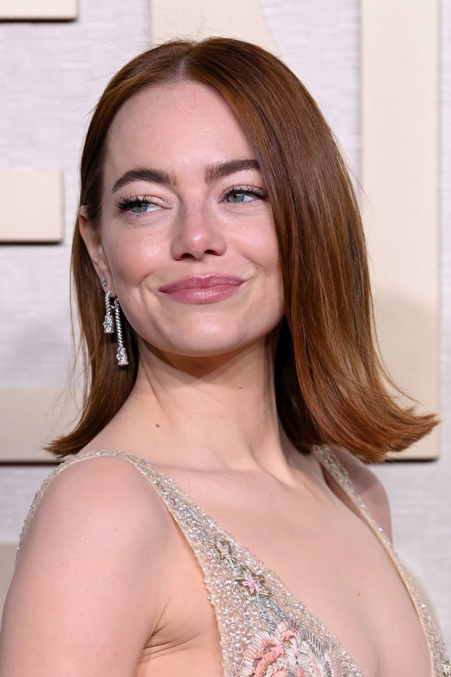 Emma Stones lució melena midi extra lisa con las puntas hacia fuera y maquillaje en tonos naturales de Charlotte Tilbury, elaborado por Rachel Goodwin. 