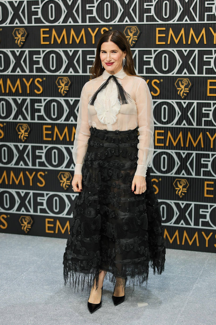 Kathryn Hahn lució un conjunto de cóctel Dior Haute Couture Primavera-Verano 2019 compuesto por camisa con pechera de organza color marfil y falda bordada en negro.