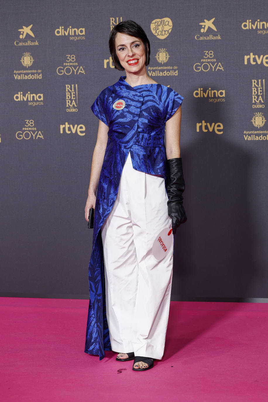 La directora de '20.000 especies de abejas' Estibaliz Urresolaeligió un curioso look formado por un pantalón oversize en color blanco y una casaca asimétrica en color azul. Lo combinó con sandalias negras y un único guante. El estilismo es de Eder Aurre. 