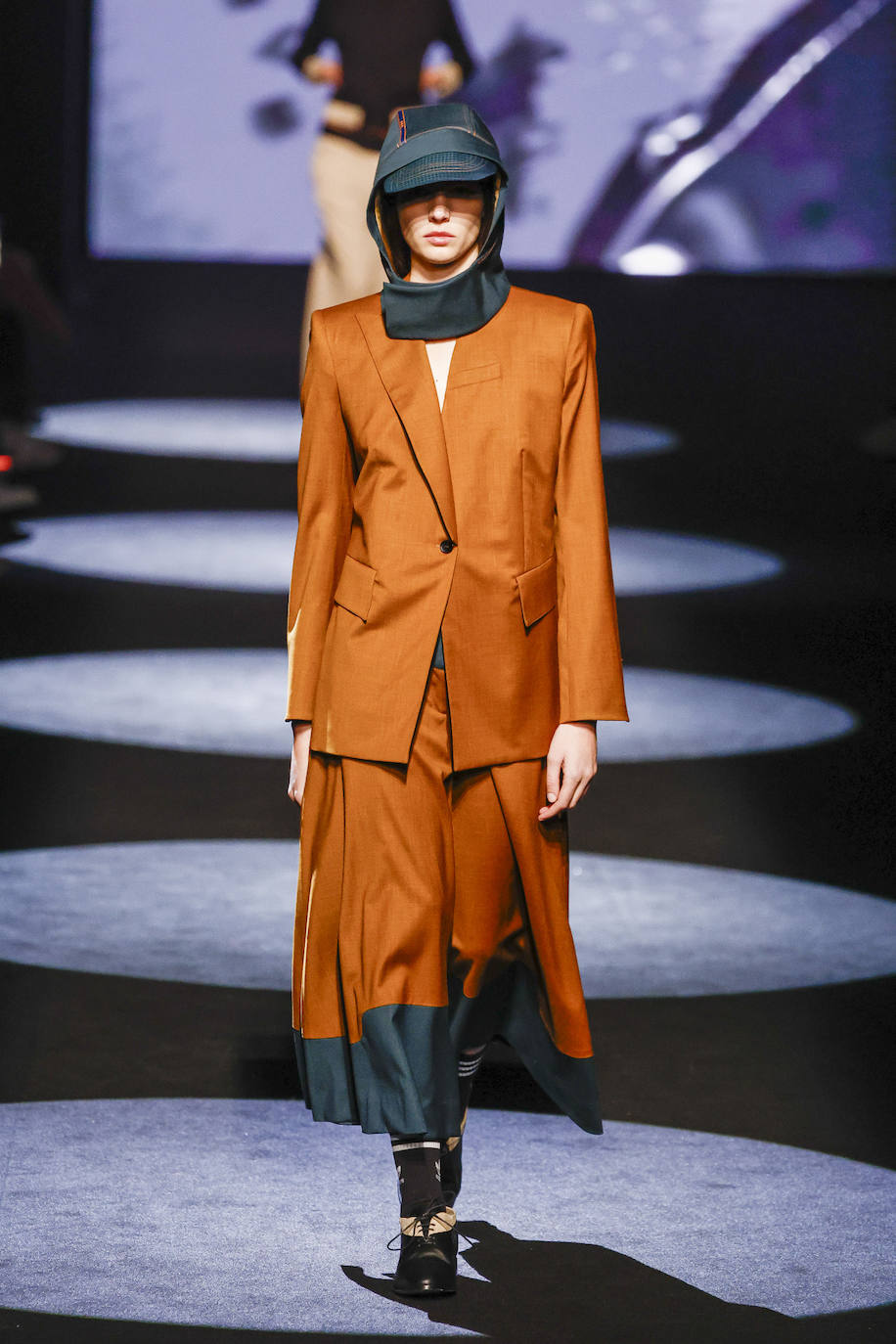 Traje de falda y chaqueta en color marrón con toque azul en el bajo. 