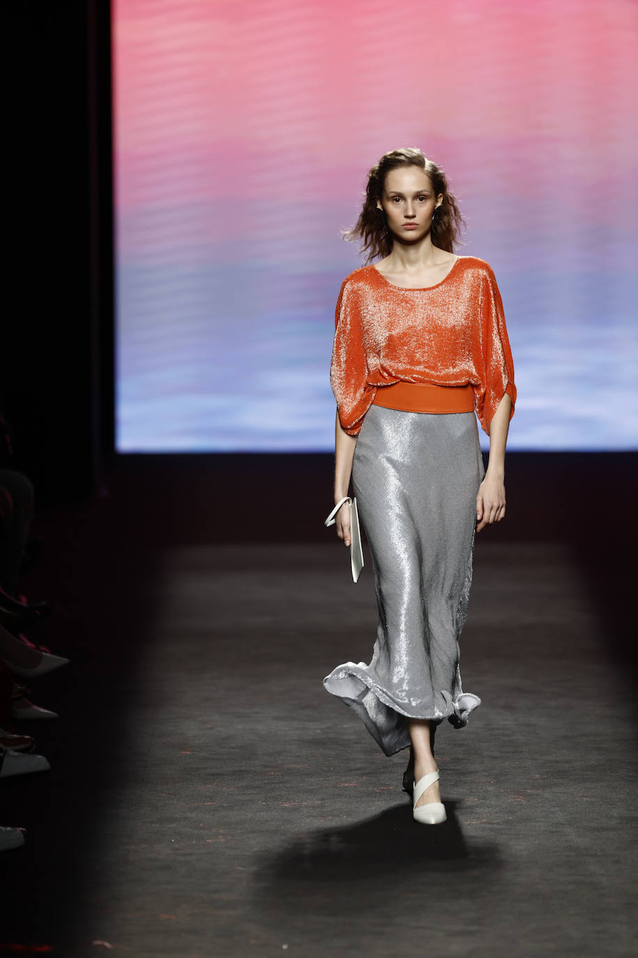 En la colección de Isabel Nuñez para el próximo otoño tampoco faltan los tejidos satinados como este conjunto de falda plateada y blusa naranja brillante. 