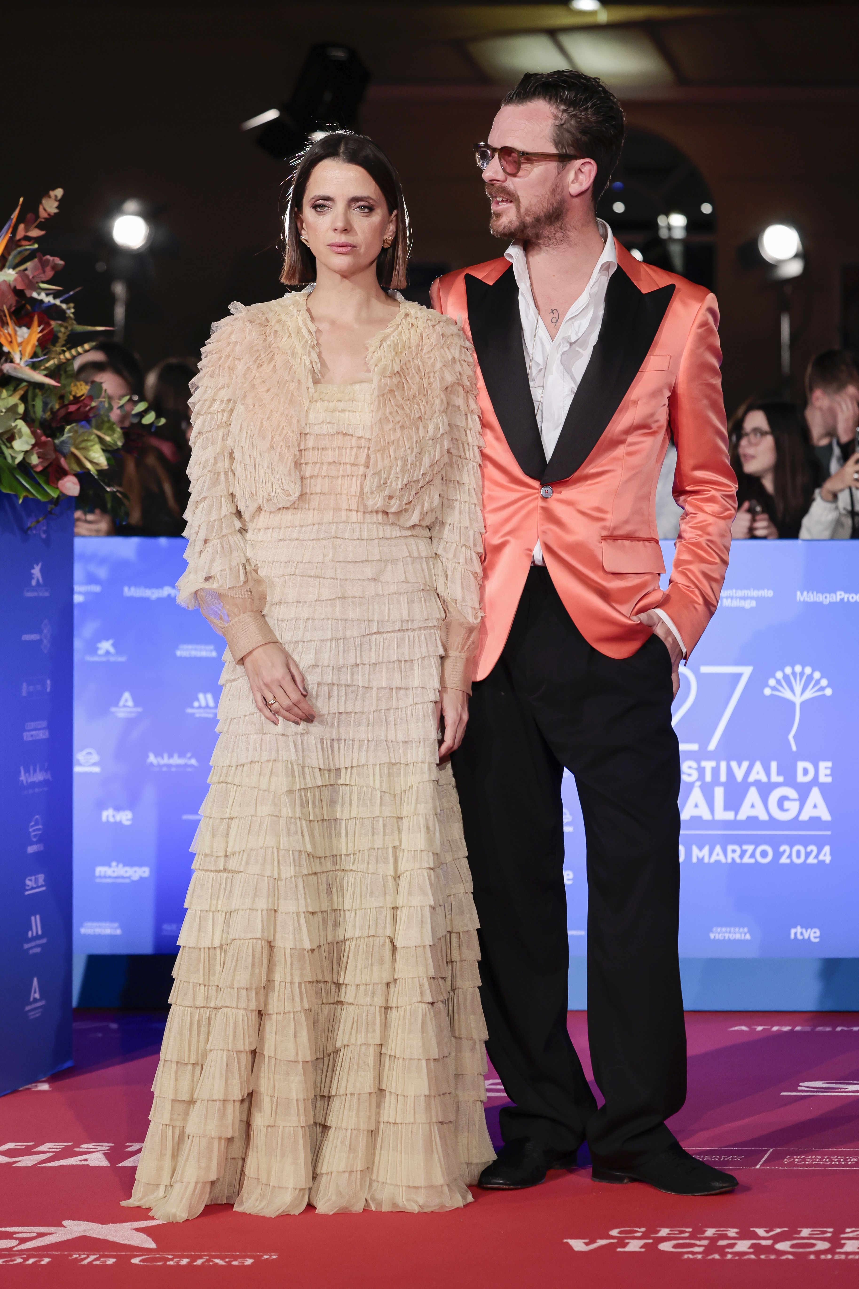 Macarena Gómez con vestido de Teresa Helbig junto a su marido Aldo Comas con una llamativa chaqueta de esmoquin en color naranja. 