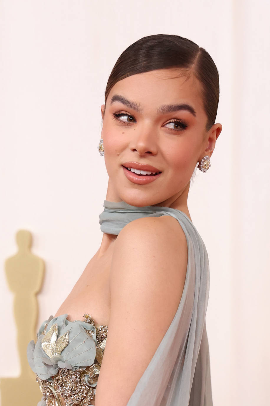 Hailee Steinfeld fue de las pocas que prefirió recoger su melena en un moño de bailarina peinado con raya lateral y acabado 'wet'. En cuanto al maquillaje, optó por el tono melocotón para sus ojos y sus labios. 