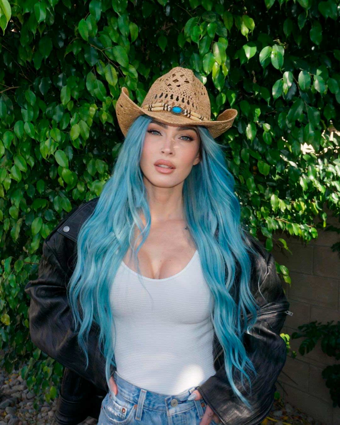 Megan Fox, con un short vaquero, camisa blanca ajustada, bomber oscura y sombrero vaquero. 