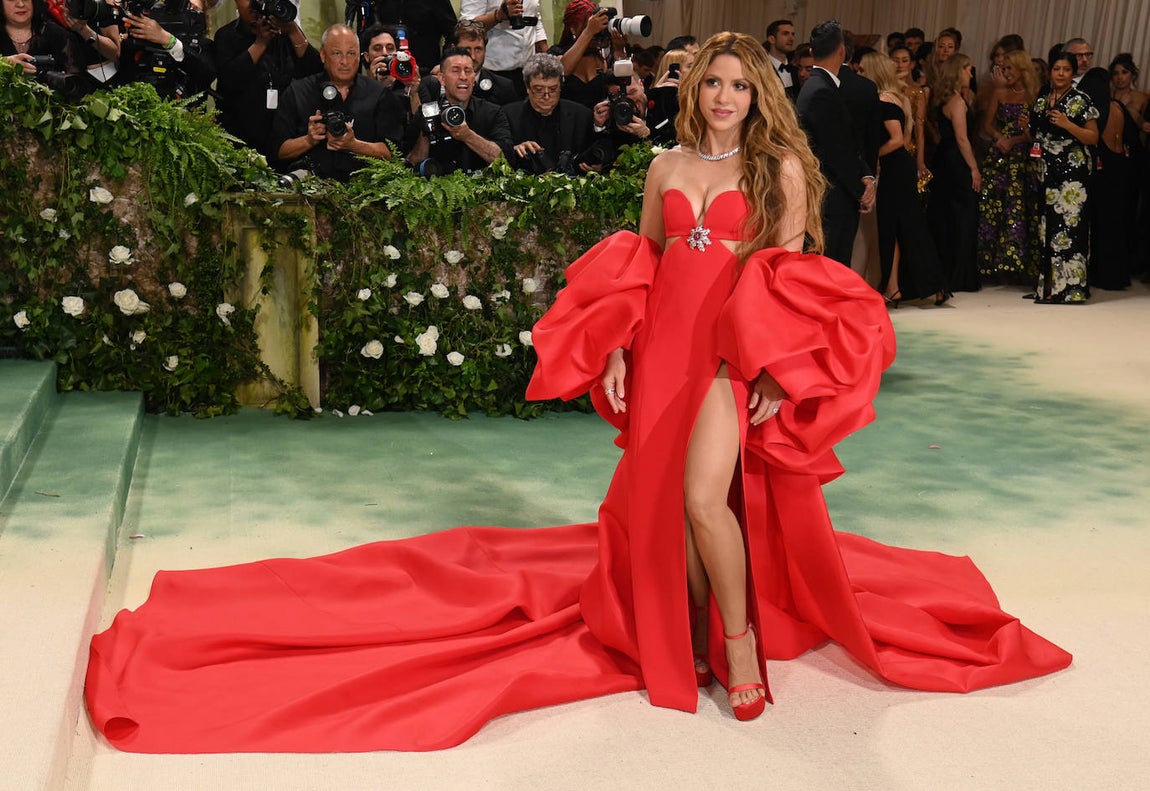Shakira posó con un vestido rojo con cola XXL, escote corazón, gran abertura lateral y mangas superpuestas, confeccionado en crepé y firmado por Carolina Herrera. EL modelo incluía una capa con cola de seda en el mismo tono. Además, llevó joyas de Cartier. 