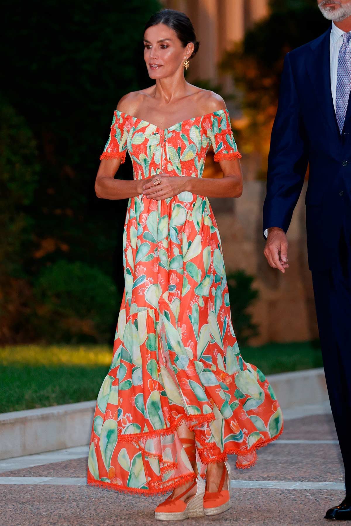 Presumiendo de moreno, la monarca acudió al Palacio de Marivent en Palma de Mallorca para recibir a la sociedad balear en el verano de 2022 con un vestido largo en tonalidades naranjas de Charo Ruiz. La pieza presentaba un favorecedor escote 'bardot' y un bonito estampado de cactus. Lo combinó con unas alpargatas con cuña a juego. 