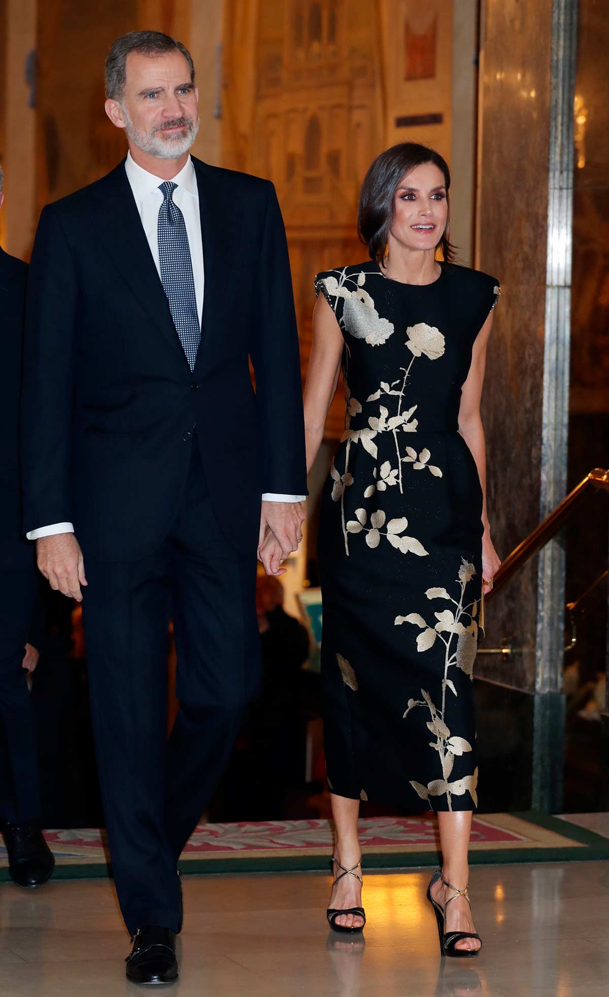 Con un falso corte de pelo 'bob' y un diseño de inspiración asiática, la Reina de España impactó en el Premio de Periodismo Francisco de Cerecedo de 2019. El diseño, en color negro, presentaba unas flores en dorado y estaba firmado por Dries van Noten.