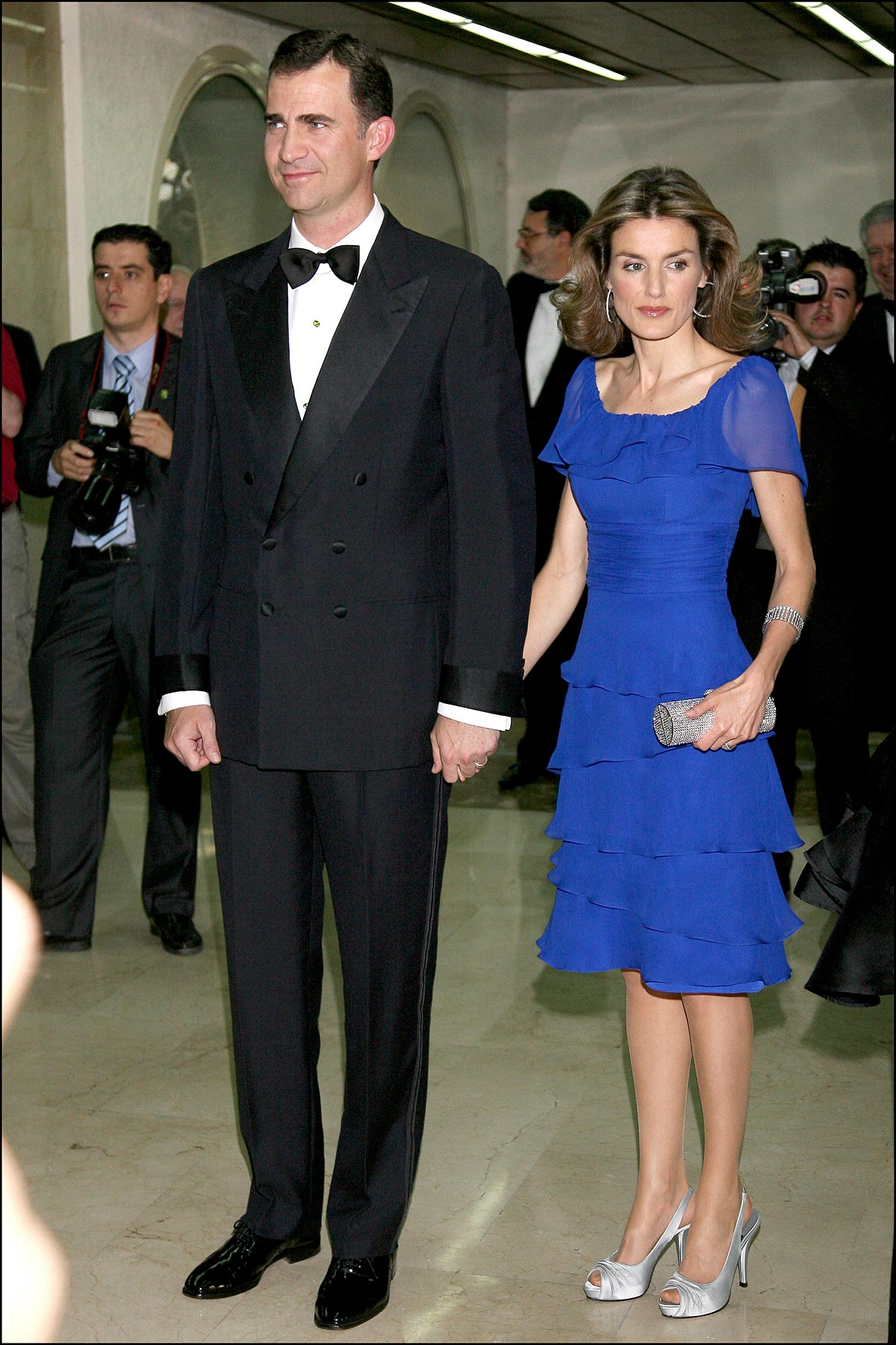 En 2008, Doña Letizia llevó un diseño azulado de manga corta y volantes de Felipe Varela. Lo completó con los famosos 'Leticios', unos 'peep-toe' que la Reina puso de moda, en color plateado y un bolso del mismo tono. 