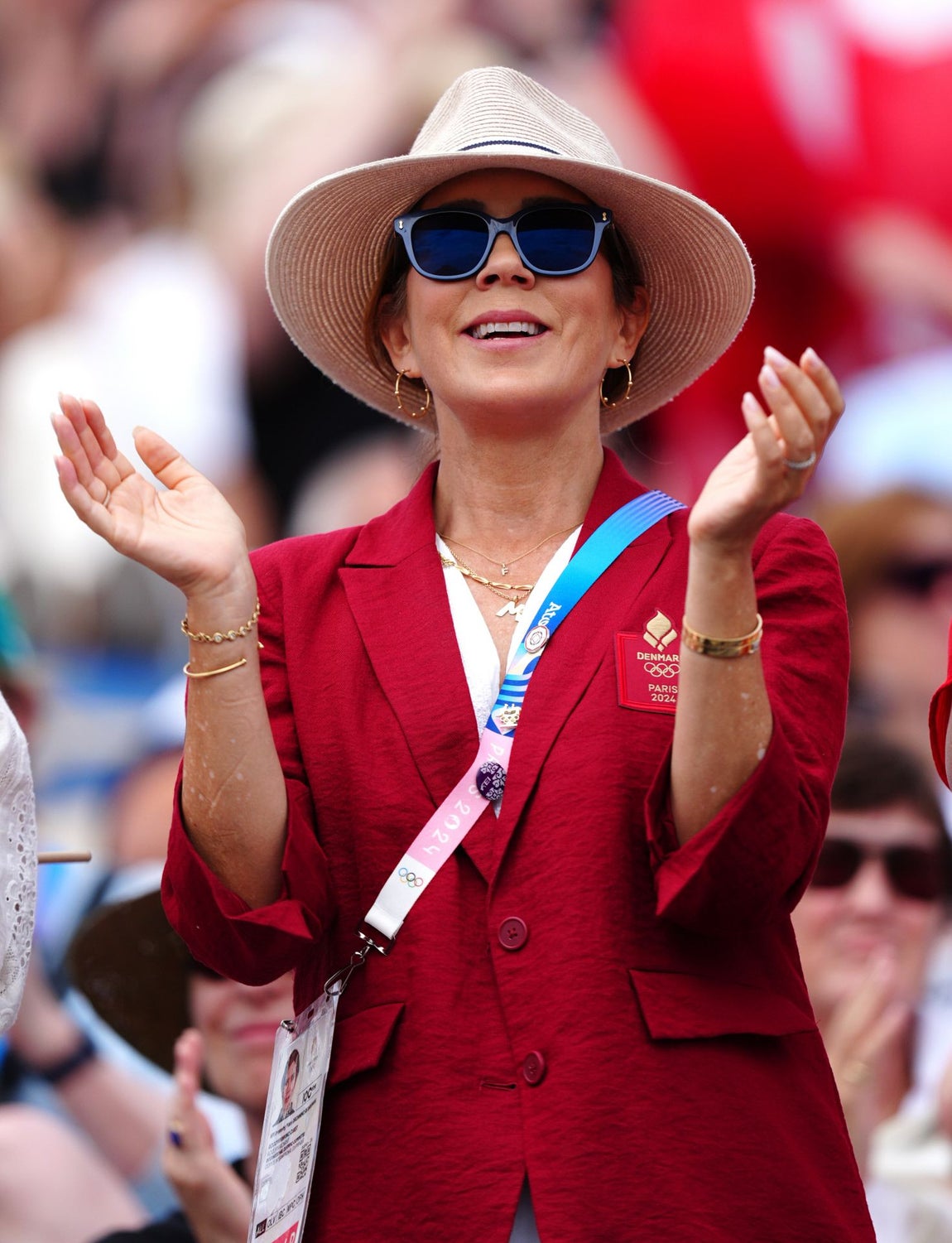 Mary de Dinamarca apostó por looks cómodos, pero elegantes. En una de sus apariciones eligió un vestido blanco de lino acompañado de una blazer en rojo, que combinó con sombrero Panamá, gafas de sol y aros dorados.