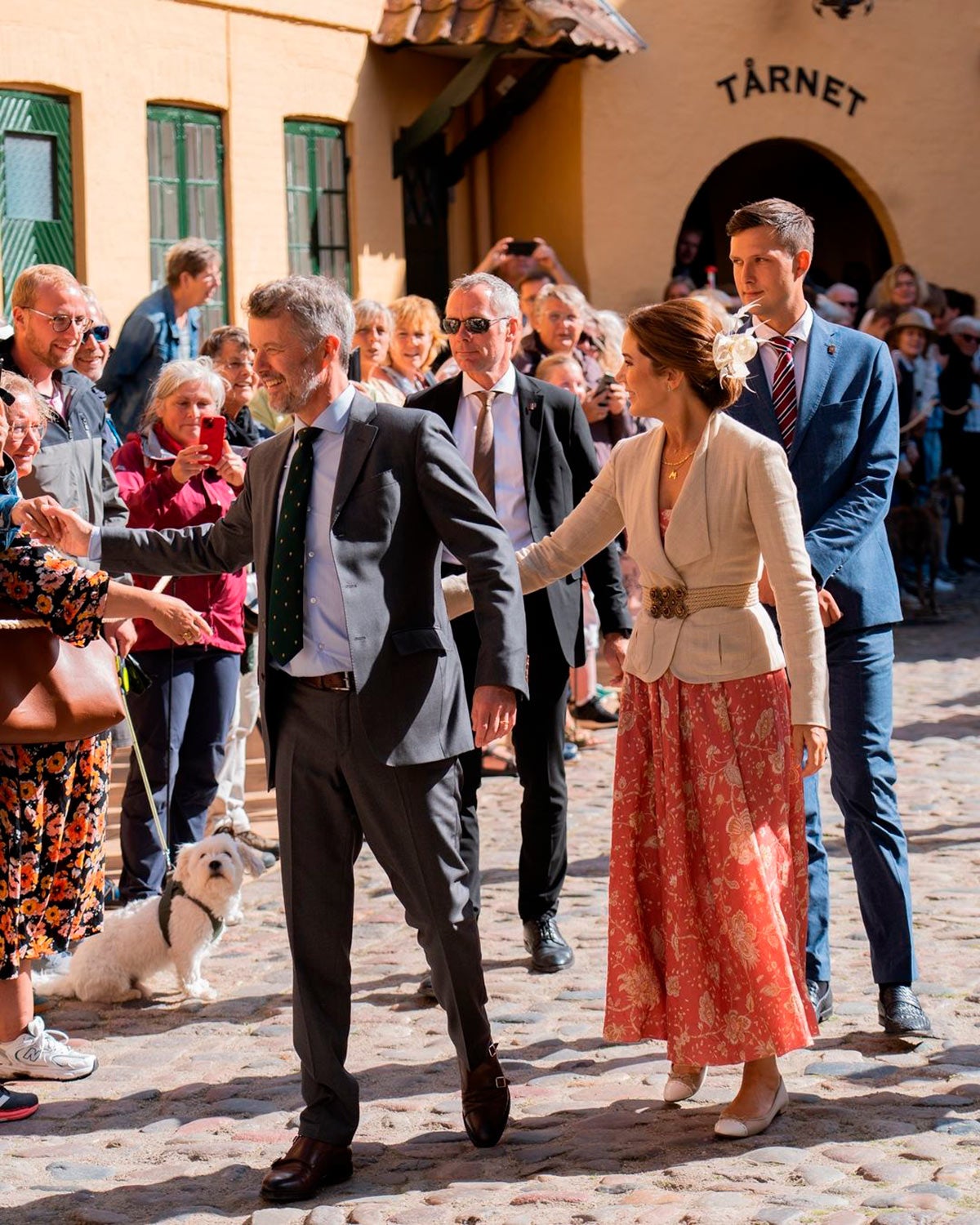 En su paso por Assens, Mary de Dinamarca lució un vestido bohemio que también tiene en su armario Máxima de Holanda. Se trata de un diseño de lino con estampado de flores firmado por Zimmermann. Para combinarlo, escogió una chaqueta de Ralph Lauren, también de lino, que acompañó con un cinturón con hebilla de pedrería de Etro. En los pies, calzado de Gianvito Rossi y un bolso de Max Mara. Además, tal y como acostumbra, remató su estilismo con un tocado en el pelo en forma de flor que llevó en un recogido. 