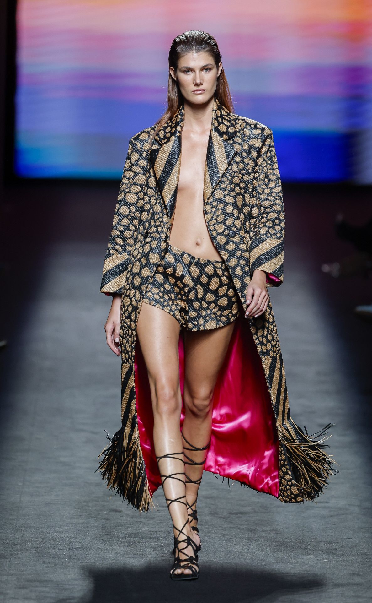 Original propuesta con un abrigo largo en piel bicolor, y forro fucsia, y minifalda de Odette Álvarez. 