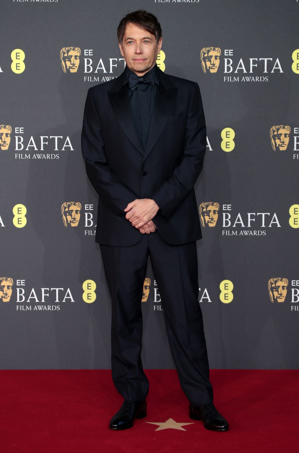 Sean Baker lució esmoquin, camisa, pajarita y zapatos en color negro, todo de Zegna. 