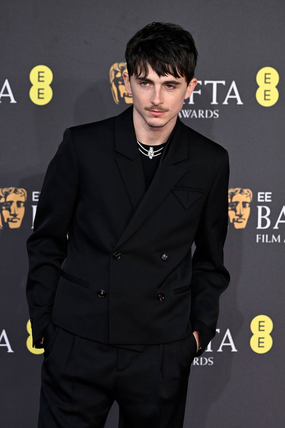 Timothée Chalamet de negro, con un traje de Bottega Veneta, y joyas de Cartier.