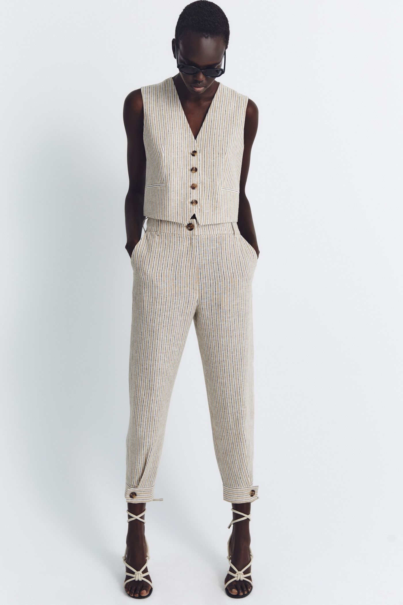 En Sfera encontramos un traje de lino con rayas en tonalidades beiges y grises en la que los botones son grandes protagonistas. Con blazer y chaleco, el pantalón, tipo bombacho, marca la diferencia con botones ajustando el bajo. Precio: blazer 59,99€, chaleco 35,99€ y pantalón 35,99€