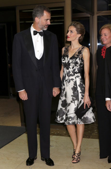 2014. Un vestido con escote de pico y sin mangas con estampado floral en tonos blancos y negros fue el escogido por Doña Letizia. El pelo recogido en un moño y unos destacables labios rojos. 