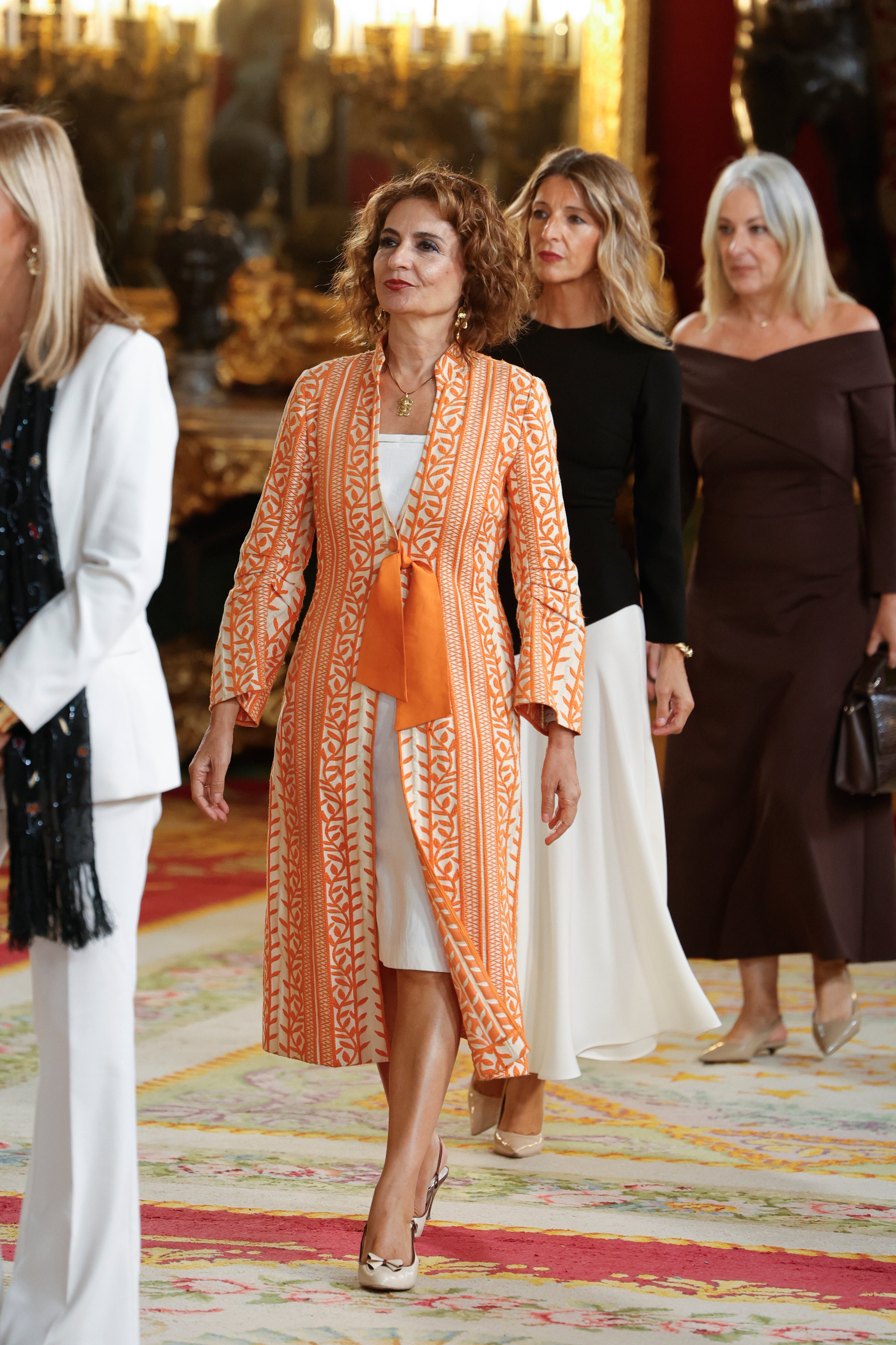 La Ministra de Hacienda, María Jesús Montero con un conjunto blanco sobre el que destaca un colorido kaftán con estampado naranja.
